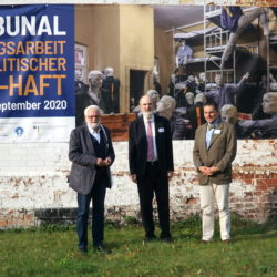 (from left to right): Karl Hafen, Thomas Schirrmacher and Dr. Sorin Muresan in front of the poster of the tribunal and the outside wall of the former Cottbus penitentiary © BQ/Martin Warnecke